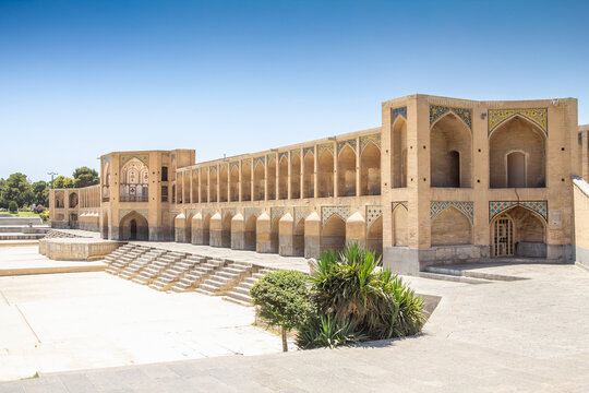 Khajoo Bridge in Isfahan, Iran, photographed in warm summer light above the dry Zayandeh River channel, combining Safavid arches and tilework with drought, water shortage and a historic landmark.