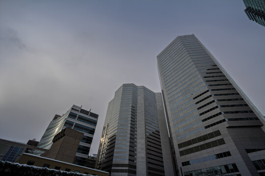 Low angle view of glass high rise office buildings in the central business district, showing a North American skyline, modern architecture and winter conditions under a cloudy sky.