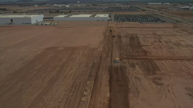 Aerial 4K video showing construction vehicles and heavy equipment preparing and grading a large area of land for development. Expansive earthworks and cleared terrain provide a useful perspective on s