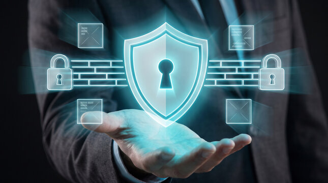 Businessman holding futuristic glowing holographic shield with keyhole and padlock wall interface icons for cyber security firewall data protection and privacy network concept