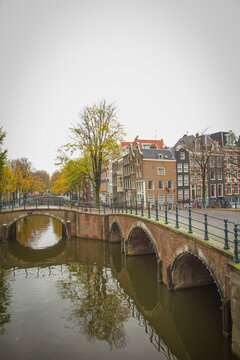 Historic brick bridges over Amsterdam canals in autumn, vertical travel background with copy space