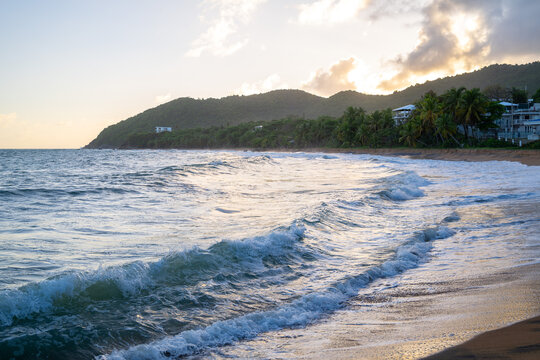 Tropical beach at sunset with ocean waves rolling onto sandy shore during golden hour