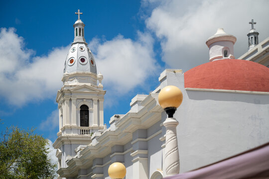 White bell tower and dome of historic catholic cathedral against blue sky with clouds in Ponce Puerto Rico
