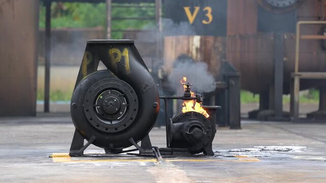 Industrial machine engine fire smoke hazard safety explosion training, industrial equipment emergency response drill with burning machinery, valve pump compressor on concrete test site