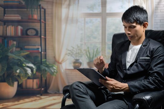 Young Man in Suit Using Tablet in Modern Interior with Plants