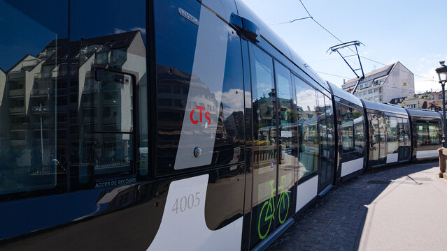 STRASBOURG, FRANCE - AUGUST 6, 2026 - Modern CTS tram moving through a sunny urban street in Strasbourg, France, reflecting buildings