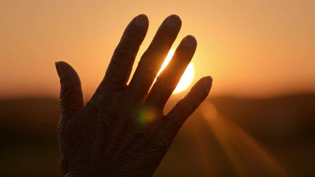 Silhouette of Hand Reaching Towards the Sun During Golden Sunset