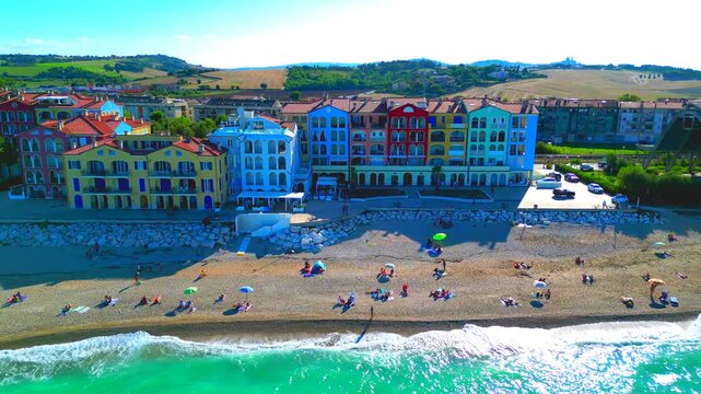 PORTO RECANATI, ITALY - JULY 30, 2025: Aerial truck left shot of the shoreside. Famous for its pastel-painted buildings and traffic-free pedestrian promenade, it offers nine km of Blue Flag beaches