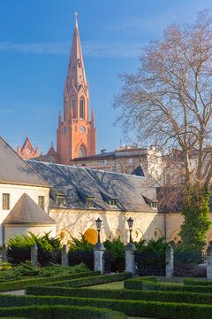 Brick church tower rising above historic buildings and landscaped gardens in Poznan, Poland.