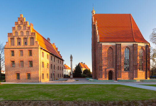 Historic Gothic church and brick buildings on Ostrow Tumski in Poznan, Poland, illuminated by warm evening light.