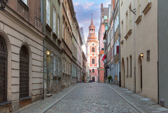 View along a cobblestone street toward the bell tower of Fara Church in the historic center of Poznan, Poland.