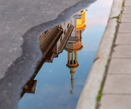 Poznan Town Hall tower reflected in a street puddle near the Old Market Square in Poznan, Poland.
