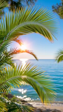 Tropical palm leaves framing a sparkling blue ocean at sunset, with warm golden sunlight shining through the lush green fronds and creating a peaceful summer vacation atmosphere.