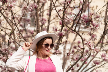 Woman Hat Spring: Woman in hat poses by blooming magnolia during spring day for photoshoot. © svetograph