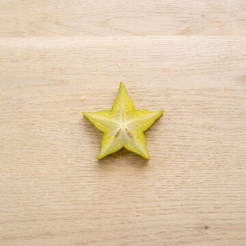 Single Slice of Star Fruit on Wooden Surface.