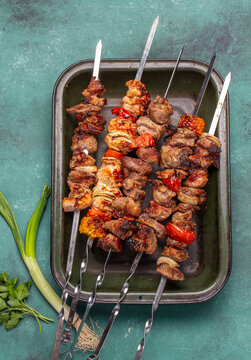 Skewers kebab filled with pork and chicken sit on a tray.