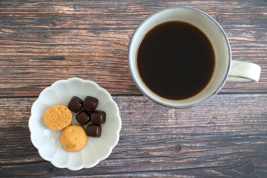 木製テーブルの上に置いたホットコーヒーとクッキーとチョコレート