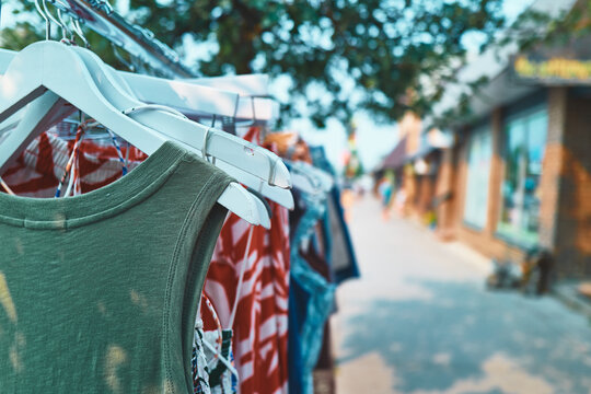 Clothing on hangers on an outdoor rack along a small town sidewalk