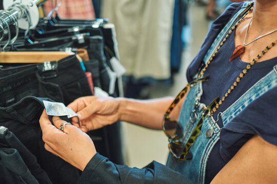 Two pairs of hands reading a clothing tag at a thrift store