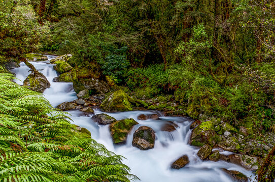 The Chasm, tuerkisfarbenes Wasser des Cleddau River zwischen bemoosten Felsbrocken, Holzsteg und Aussichtsplattform im Hintergrund, Milford Road, Fiordland National Park, Suedinsel, Neuseeland