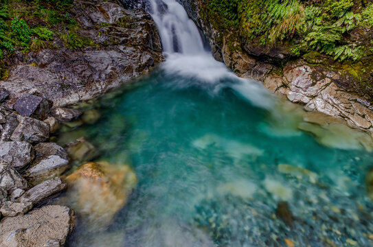Christie Falls, kaskadenartiger Wasserfall stuerzt in tuerkisfarbenen Gumpen, umrahmt von bemoosten Felsen und dichtem Regenwald, Fiordland National Park, Southland, Suedinsel, Neuseeland