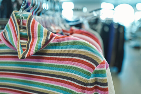 Multicolored striped knit sweater on a hanger at a thrift store