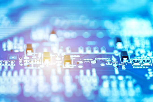 Abstract close-up of an electronic circuit board with blurred components and glowing light effects. Digital technology and innovation concept.
