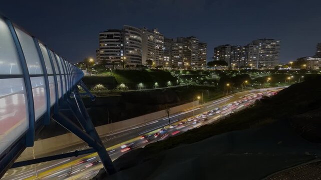 Night-time time-lapse of Armendariz Avenue in Lima, Peru, showing cars driving along the avenue at night. A night view of modern buildings.