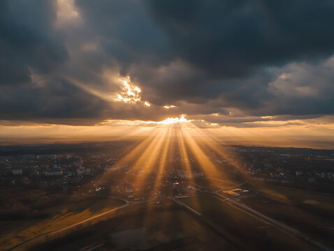 Dramatic sunset over a cityscape with powerful sun rays through clouds.