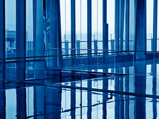 Fototapeta premium Spacious glass atrium with reflections on polished floor and panoramic windows. Empty lobby features