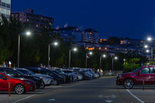 Cars parked under streetlights beside apartments at night