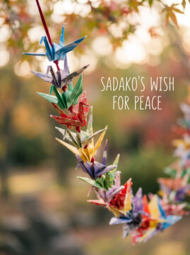 Hanging Garland of Colorful Folded Origami Paper Cranes in Green Garden