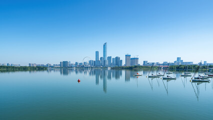 Fototapeta premium Modern City Skyline Reflected in Calm Lake with Sailboats