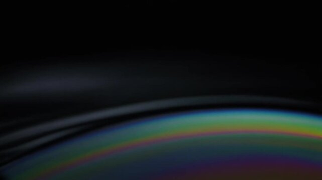 Concentric ripple rings expand gently across dark still water, catching soft raking light along each crest in a serene indigo and silver cinematic composition with generous copy space.