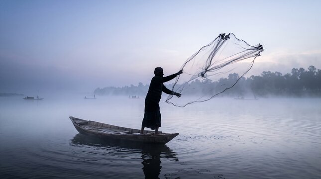 Silhouette of traditional fisherman throwing cast net from wooden boat into misty lake on foggy winter morning.