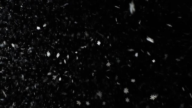 A close-up view of snowflakes falling against a dark background.