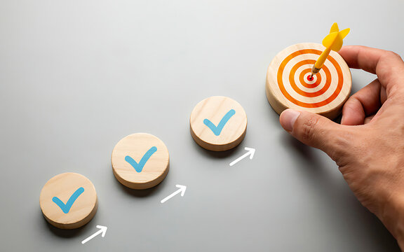 Hand placing a wooden target block with yellow dart next to completed checkmark progress steps