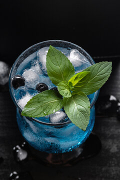 Blue Sparkling Cocktail With Blueberries Mint and Ice on Black Background