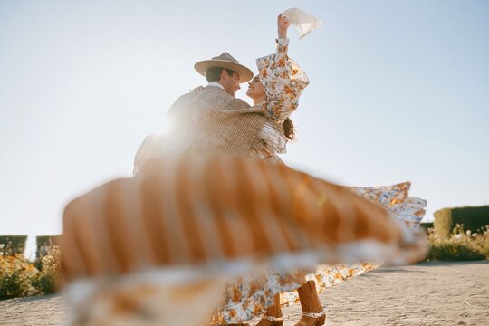 Chilean huaso and partner dancing the cueca in traditional dress under a bright sun, a joyful cultural celebration for national heritage and tourism