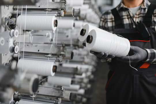 Worker holding polypropylene thread spool in textile factory