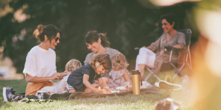 Multi generational family picnic in the park featuring a young girl with a cochlear implant for inclusive lifestyle and outdoor leisure concepts
