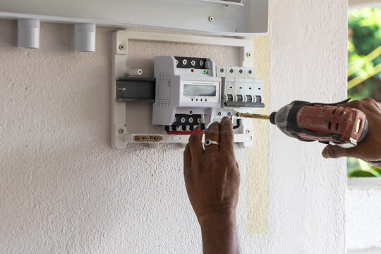 Closeup of technician installing solar photovoltaic hybrid inverter into a residential house