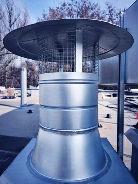 Detailed view of stainless steel vent cap on commercial building roof during maintenance check