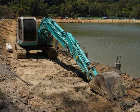 Building process city levee. Excavator dredging pond bank