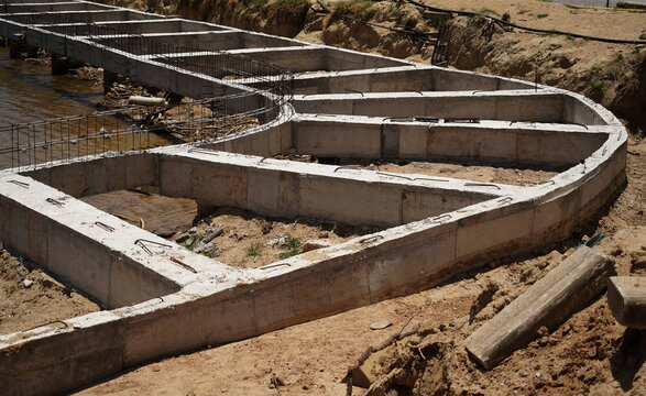 Building process city levee. Exposed foundation rebar grid at site, standing formwork and concrete footings