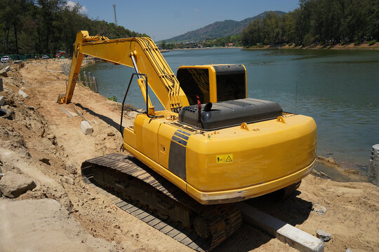 Building process city levee. Excavator dredging pond bank