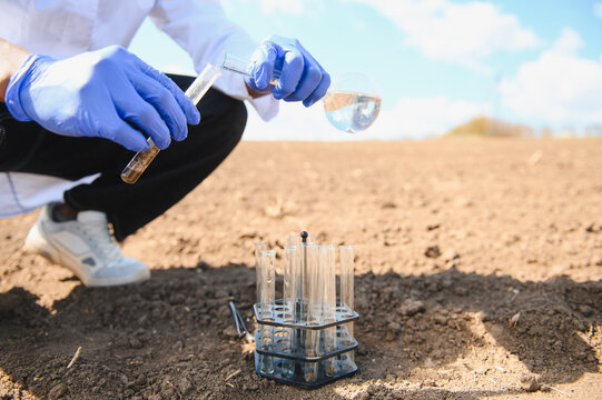 Agronomist scientist analyzing soil in field for research