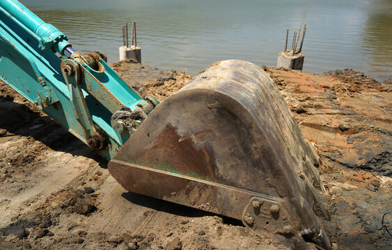 Building process city levee. Excavator dredging pond bank
