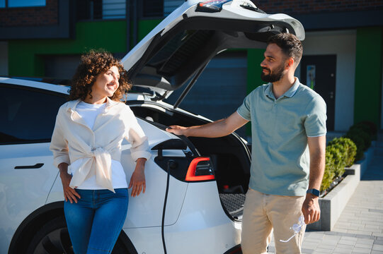 Couple charging electric car at home, embracing green energy and sustainable lifestyle