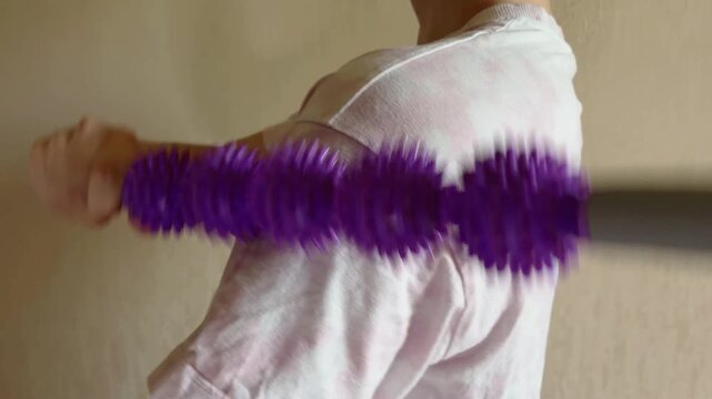 Woman relieving muscle pain and tension in neck, shoulders, and back using a purple spiky massage roller stick for self massage and physical therapy at home